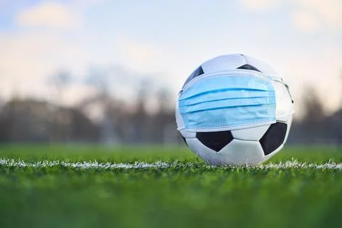 Soccer Ball In Medical Mask On Empty Stadium. Football Cancellation Concept Stock Photos