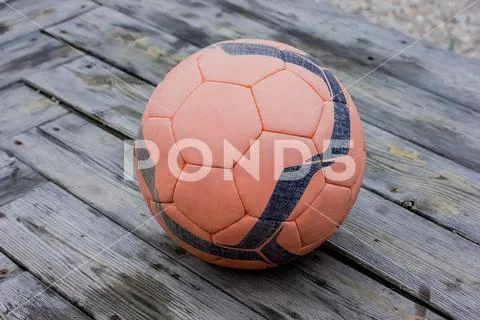 A soccer ball with a pattern lies on the wooden floor. Stock Photos