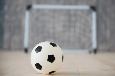 A soccer ball in a small gate on a gray background. Mini football. Stock Photos