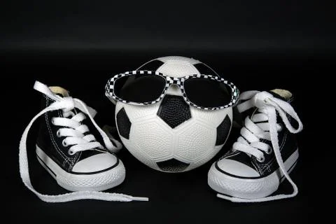 Soccer ball with sunglasses and black and white sneakers Stock Photos