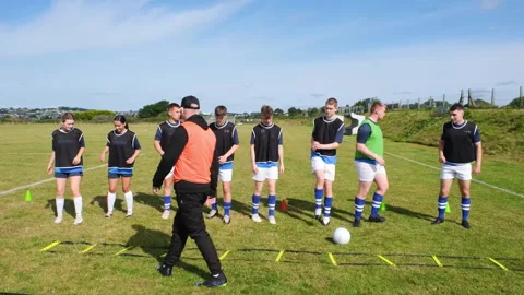 Soccer coach guiding team through agility drills on sunny field Stock Footage 310132828
