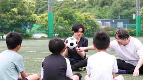 Soccer Coaches Explaining Tactics to Japanese Children on Field 스톡 동영상 344240765