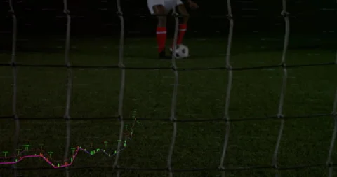 Soccer forward running under lights and striking ball to score goal through net 库存影片 311585938