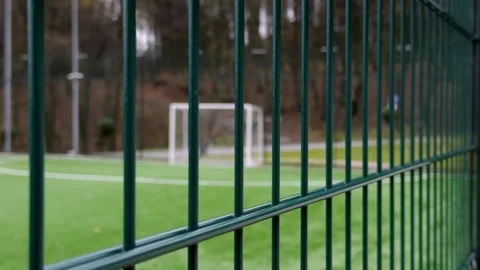 A soccer goal is set against the backdrop of a vibrant green fence on a Stock Footage 305270330