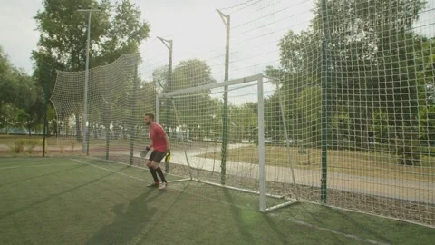 Soccer goalkeeper making diving save on football pitch at daybreak Stock Footage 157416730