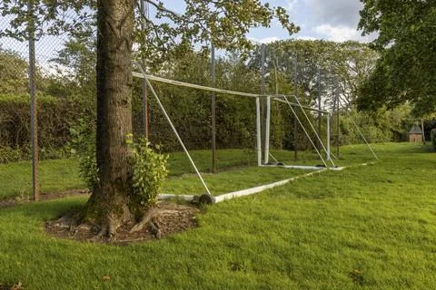 Soccer goalposts stand below trees and beside chain-link fence Stock Photos