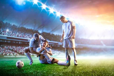 Soccer player helps onother one on sunset stadium background panorama Stock Photos