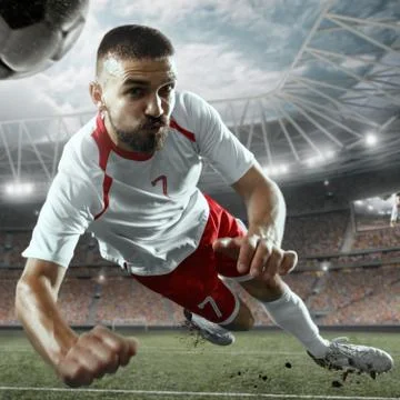 Soccer player performs an action play on a professional stadium Stock Photos