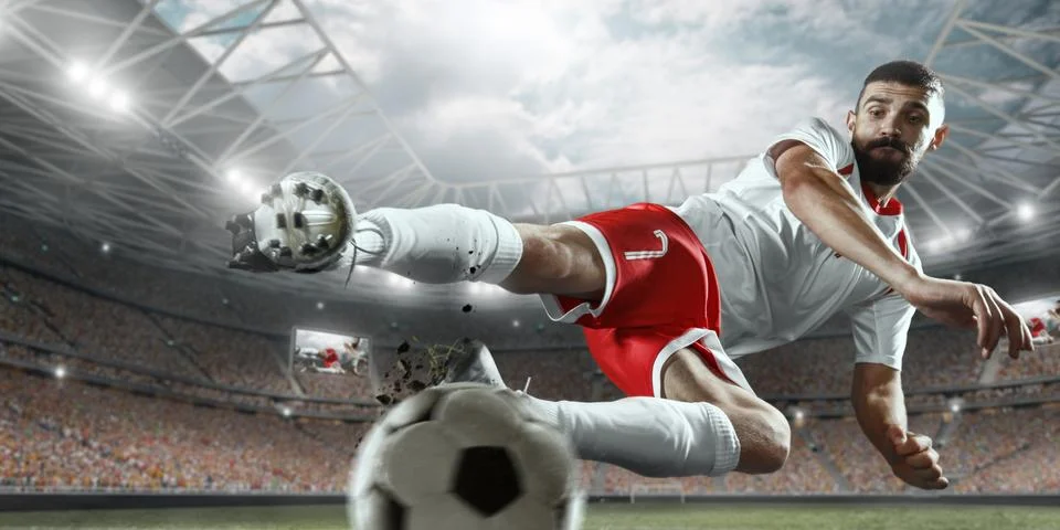 Soccer player performs an action play on a professional stadium Stock Photos