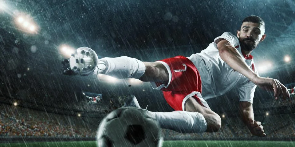 Soccer player performs an action play on a professional stadium Stock Photos