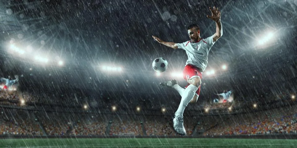 Soccer player performs an action play on a professional stadium Stock Photos