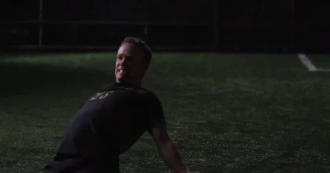 A soccer player slides to a stop on his knees during a night game. Slow motion. Stock Footage 69214265