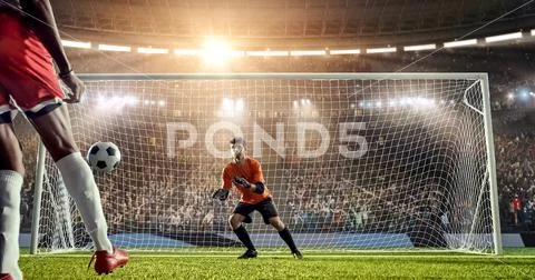 Soccer player is trying to score a goal while goalkeeper defends Stock Photos