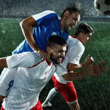Soccer players performs an action play on a professional stadium Stock Photos