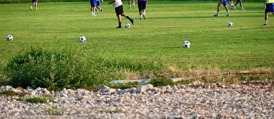 Soccer practice session with multiple balls on a green grass field Stock Photos