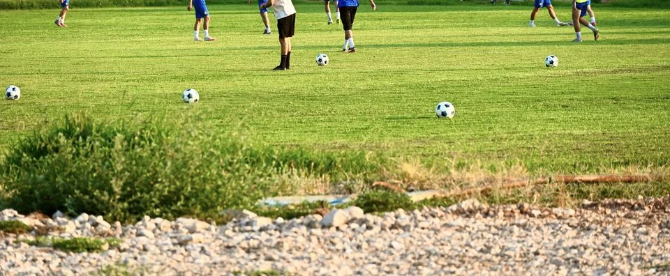 Soccer practice session with multiple balls on a green grass field Stock Photos