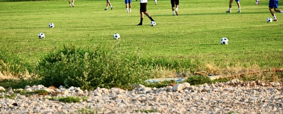 Soccer practice session with multiple balls on a green grass field Stock Photos