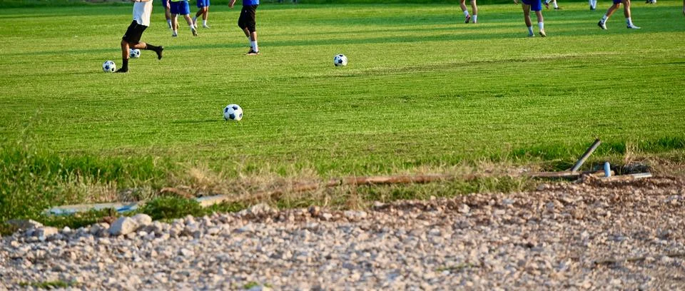 Soccer practice session with multiple balls on a green grass field Stock Photos