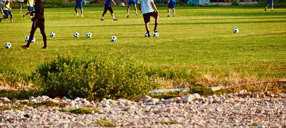 Soccer practice session with multiple balls on a green grass field Stock Photos