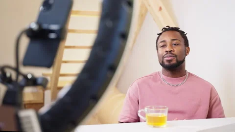 Sociable positive guy creating video content using smartphone and ring lamp. Stock Footage 262692849