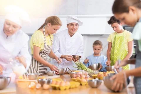 Sociable young chef leading culinary courses to group of tweens Stock Photos