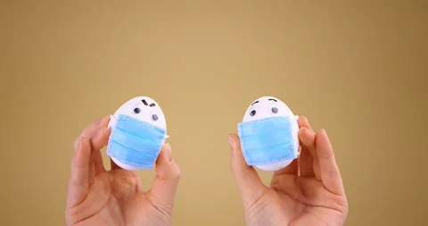 Social Distance. Cute Easter Eggs in protective medical masks in hands during Stock Footage 150959823