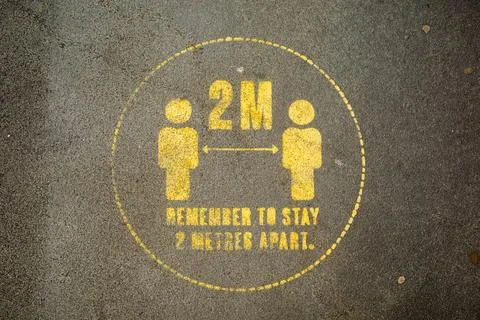Social Distancing Please keep 2 metres apart yellow sign on pavement Stock Illustration