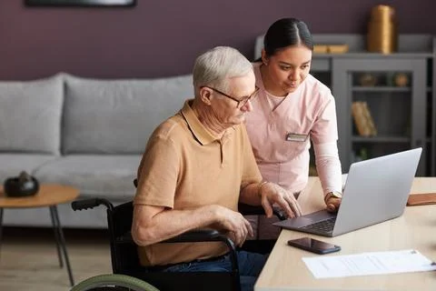 Social worker teaching elderly man how to use a computer Stock Photos