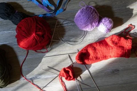 Sock in the process of knitting with needles and yarn of red color Foto stock