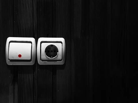 Socket and light switch on a black wooden wall. Stock Photos