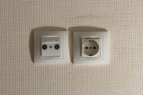 Socket and socket for the TV antenna cable on the beige wall Stock Photos