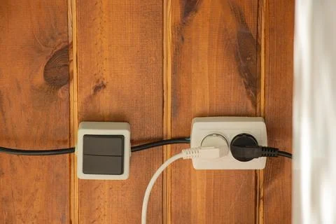 Socket and switch on a wooden wall outside, plastic sockets Stock Photos