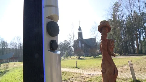 Socket of electric car charging station. Wooden church building in background Stock Footage 113404951