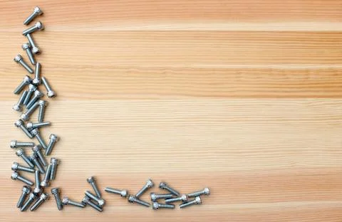 Socket head screws as L-shape border on woodgrain background Fotos Stock
