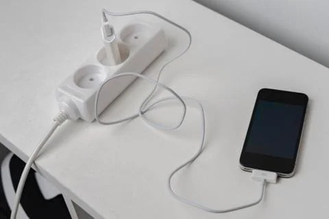 Socket with a phone wire quick charger on the white shelf Foto stock