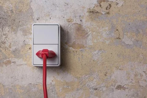 Socket with red wire on grungy wall Foto stock