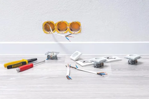 Sockets and cable in the wall, lying pliers on the floor, a screwdriver, sock Stock Photos