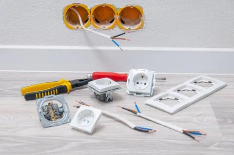 Sockets and cable in the wall, lying pliers on the floor, a screwdriver, sock Stock Photos