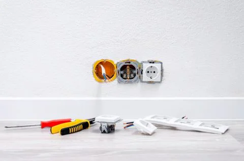 Sockets and cable in the wall, lying pliers on the floor, a screwdriver, sock Stock Photos