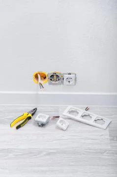 Sockets and cable in the wall, lying pliers on the floor, a screwdriver, sock Stock Photos