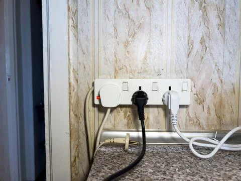 Sockets in the wall, wires in the socket on the kitchen wall, overloaded wall Stock Photos