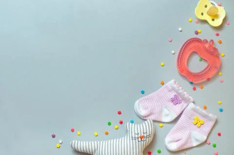 Socks, soother, teether and sleeping cat toy over grey background Stock Photos