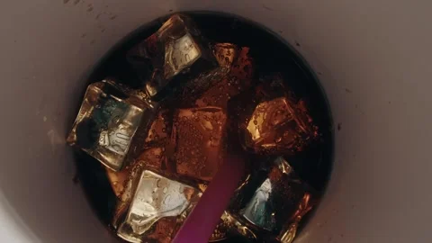 Soda with Ice Cubes in a Plastic Cup Being Stirred with a Purple Straw 库存影片 331098689
