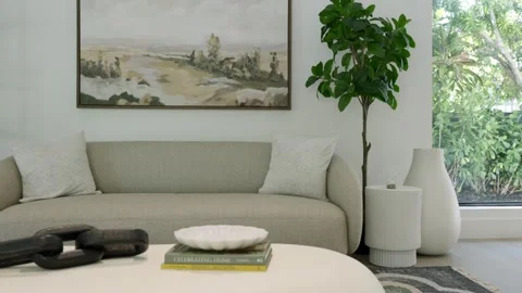 Sofa garnished with light pillows standing opposite coffee table decorated with Stock Footage 280419235