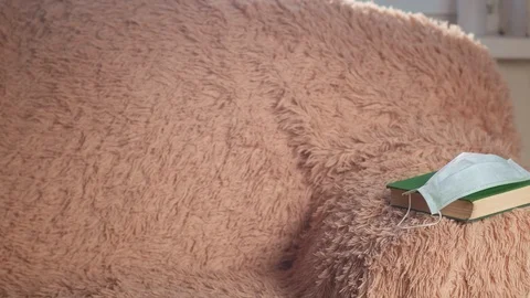 Sofa with a plaid and a book on which a medical mask, camera movings Stock Footage 129430122