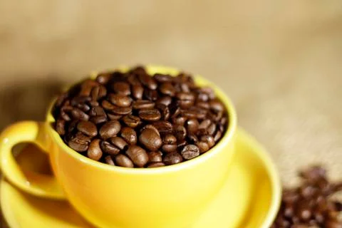 Сoffee beans in a yellow cup Stock Photos