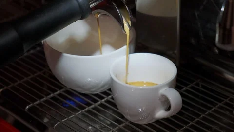 Сoffee trickling from a modern machine into two different sized cups Stock Footage 106372352