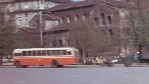 Sofia - 1967: Red buses and cars on the street a man crosses the road with a kid Video stock 168601007