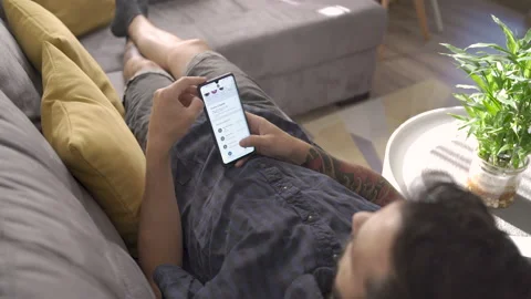 Sofia, Bulgaria-07 08 2021: Man using revolut on smartphone resting on a sofa Vidéo 159881552