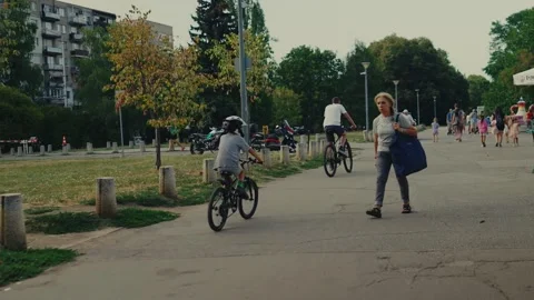 SOFIA, BULGARIA - AUGUST 29, 2026: Boy wearing helmet riding bicycle along park 動画素材 345901496